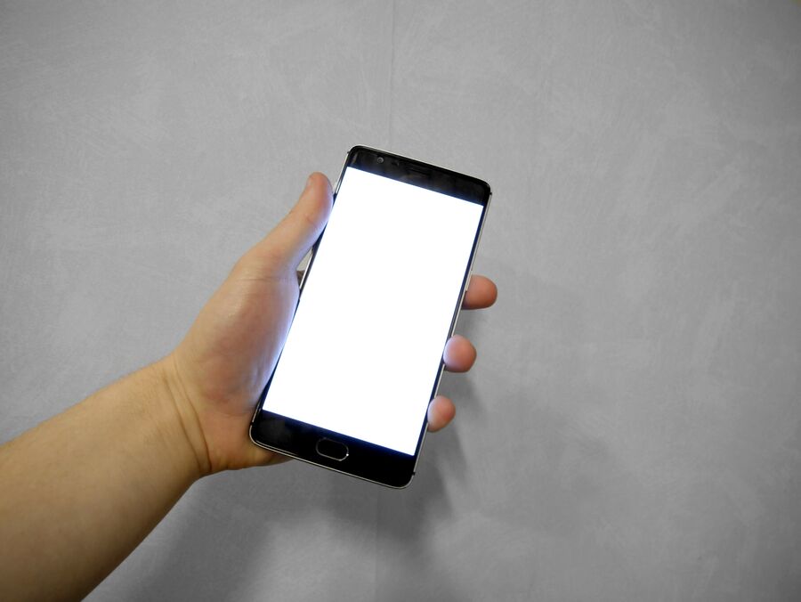 Mano sosteniendo un teléfono móvil con la pantalla encendida